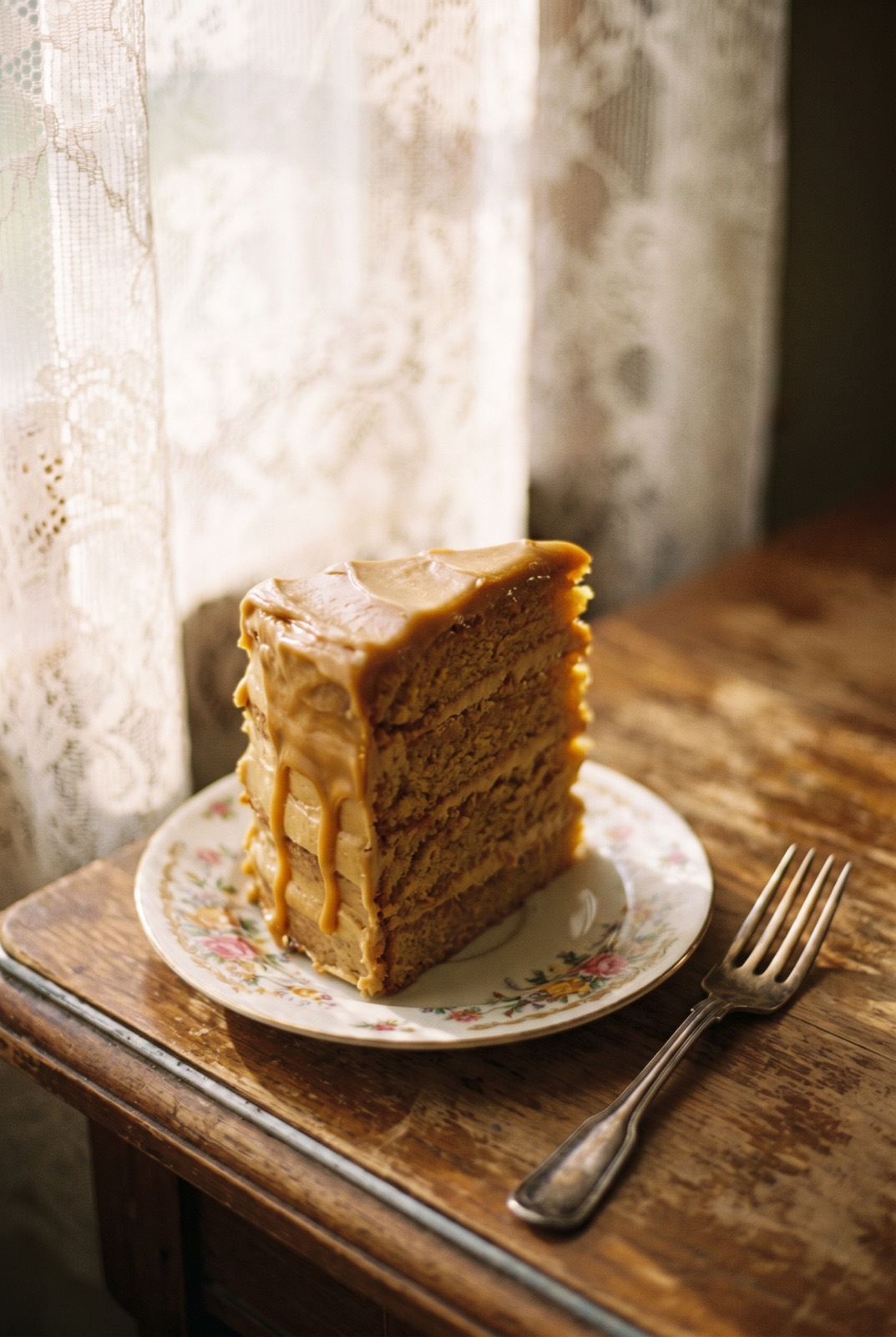Caramel layer cake slice on a vintage floral saucer