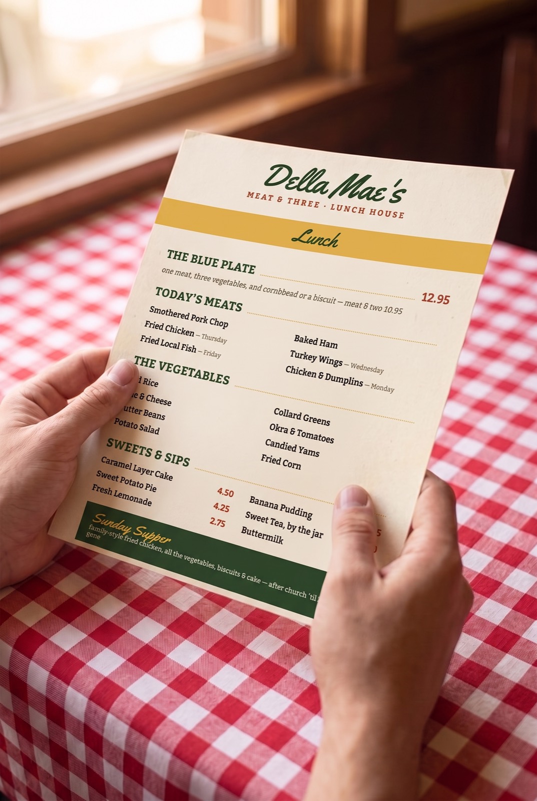 Hands holding the printed Della Mae's lunch menu at a gingham table