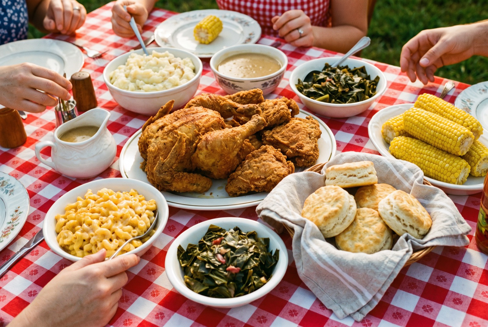 Sunday supper: fried chicken platter, sides, and biscuits with hands reaching in